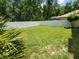 A spacious fenced-in backyard, featuring lush green grass and mature trees, provides privacy and a serene outdoor setting at 1941 Spruce Creek Lndg, Port Orange, FL 32128
