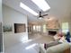 Bright living room featuring skylights, a ceiling fan, and a stone fireplace, creating a cozy and inviting atmosphere at 1941 Spruce Creek Lndg, Port Orange, FL 32128