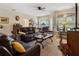 Comfortable living room featuring hardwood floors, plush leather seating, and large windows with natural light at 1983 Turnbull Lakes Dr, New Smyrna Beach, FL 32168