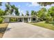 Charming single-story home with a spacious driveway and lush green lawn surrounded by mature trees at 200 W Washington Ave, Deland, FL 32720