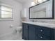 Updated bathroom featuring blue vanity with marble top, white tile floor, and a modern framed mirror at 210 Delespine Dr, Debary, FL 32713