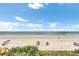 Wide shot of the beach with distant figures enjoying the ocean, framed by vegetation at 2101 Hill St, New Smyrna Beach, FL 32169