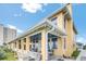 Charming two-story home featuring a covered porch with seating, surrounded by a landscaped yard, and blue skies at 2101 Hill St, New Smyrna Beach, FL 32169