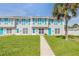 Townhouses with vibrant turquoise shutters and doors, set against a backdrop of a neatly maintained lawn and palm trees at 2122 S Atlantic Ave # 2122, New Smyrna Beach, FL 32169