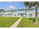 Charming townhouses with turquoise shutters and doors, complemented by a lush green lawn and mature palm trees at 2122 S Atlantic Ave # 2122, New Smyrna Beach, FL 32169