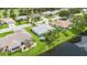 Aerial view of a home with a well-manicured yard, backing onto a lake, in a residential neighborhood at 223 Ne Golf Club Dr, New Smyrna Beach, FL 32168