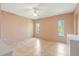 Spacious bedroom with neutral walls, tile floors, ceiling fan, and windows overlooking the lush landscaping at 223 Ne Golf Club Dr, New Smyrna Beach, FL 32168