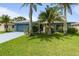 Charming single-story home with lush green lawn, colorful flowers, and mature palm trees at 223 Ne Golf Club Dr, New Smyrna Beach, FL 32168