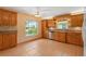 Sunlit kitchen boasting wooden cabinets, tile flooring, and backyard views at 223 Ne Golf Club Dr, New Smyrna Beach, FL 32168