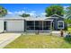 Gray single story home with a two car garage, manicured lawn, and a screened in porch at 2325 Lime Tree Dr, Edgewater, FL 32141