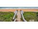 Wooden walkway leading to a sandy beach with ocean views, surrounded by grassy dunes at 25 Dolphin Ave, Ormond Beach, FL 32176