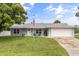 Charming single-story home features a well-manicured lawn, American flag, and inviting front porch seating area at 2529 Umbrella Tree Dr, Edgewater, FL 32141