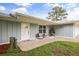 Charming single-story home features a well-manicured lawn, inviting front porch seating, and stylish front door at 2529 Umbrella Tree Dr, Edgewater, FL 32141