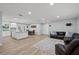 Open-concept living room features modern lighting, wood flooring, and flows into a kitchen and dining area at 2529 Umbrella Tree Dr, Edgewater, FL 32141