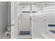 Bathroom with white tile walls, shower, and glass block window for natural light at 2632 Turnbull Estates Dr, New Smyrna Beach, FL 32168