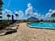 View of the community pool area, blue skies, palm trees and lounge chairs for residents to enjoy at 2700 N Peninsula Ave # 322, New Smyrna Beach, FL 32169