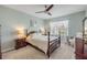 Comfortable bedroom with a wooden bed frame, matching nightstands, ceiling fan, and view of the outdoor greenery at 2733 Neverland Dr, New Smyrna Beach, FL 32168