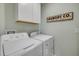 Functional laundry room featuring a modern washer and dryer set with overhead cabinets and laundry-themed decor at 2733 Neverland Dr, New Smyrna Beach, FL 32168