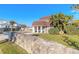 Charming home exterior with mature landscaping, a stone wall, a well-manicured lawn, and a brick-lined driveway at 2900 S Peninsula Dr, Daytona Beach, FL 32118