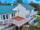 Spacious back deck with multiple levels, white railings, and stairs to lush grounds, metal roof above at 2950 Sunset Dr, New Smyrna Beach, FL 32168