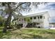 Inviting two-story home featuring a charming front porch, well-manicured lawn, and lush landscaping at 2950 Sunset Dr, New Smyrna Beach, FL 32168