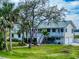 Charming two-story home boasting lush landscaping, a metal roof, and inviting staircases to elevated porches at 2950 Sunset Dr, New Smyrna Beach, FL 32168