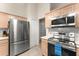 Modern kitchen featuring stainless steel appliances, light wood cabinets, and tiled flooring at 3231 Bretton Woods Ter, Deltona, FL 32725