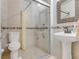 A tiled bathroom featuring a glass door shower, toilet, and pedestal sink at 3326 S Peninsula Dr, Port Orange, FL 32127