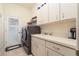 Clean laundry room with modern washer and dryer, ample counter space, and overhead cabinets at 3577 Maribella Dr, New Smyrna Beach, FL 32168