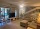 Comfortable living room with plush carpet, neutral tones, and access to a bright sunroom; has stairs to 2nd level at 38 Cedar Dunes Dr, New Smyrna Beach, FL 32169