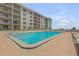 Bright pool with lounge chairs and brick surface, located within view of residential tower at 4151 S Atlantic Ave # 3090, New Smyrna Beach, FL 32169