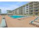 View of a stunning pool with chairs lined up, surrounded by upscale condo buildings at 4151 S Atlantic Ave # 3090, New Smyrna Beach, FL 32169