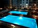 Nighttime view of two illuminated swimming pools surrounded by lounge chairs in a serene setting at 4151 S Atlantic Ave # 3090, New Smyrna Beach, FL 32169
