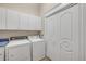 Bright laundry room featuring a washer, dryer, cabinets and bi-fold doors at 423 S Atlantic Ave # 301, New Smyrna Beach, FL 32169