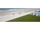 An aerial view of a sandy beach with people relaxing under tents and umbrellas next to a pool and green lawn at 4435 S Atlantic Ave # 416, Port Orange, FL 32127
