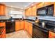 Well-lit kitchen featuring custom wood cabinets, granite countertops, and modern black appliances at 4435 S Atlantic Ave # 416, Port Orange, FL 32127