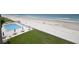 Aerial view of a community pool near a sandy beach, with lounge chairs and tables with umbrellas at 4435 S Atlantic Ave # 416, Port Orange, FL 32127