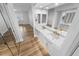 Bright bathroom features double sinks with gold fixtures and a mirrored wall, complemented by wood-look floors at 4620 Riverwalk Village Ct # 7403, Ponce Inlet, FL 32127