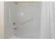 All-white tiled bathtub and shower combination featuring safety grab bars at 511 Mount Olympus Blvd, New Smyrna Beach, FL 32168