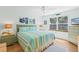 Bright bedroom featuring a queen bed with striped bedding, a ceiling fan, and a large window at 511 Mount Olympus Blvd, New Smyrna Beach, FL 32168