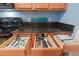 Close up of kitchen drawers featuring wood cabinets, black appliances, and granite countertops at 511 Mount Olympus Blvd, New Smyrna Beach, FL 32168