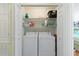 Laundry closet with stacked washer and dryer, wire shelving, and white bi-fold doors at 511 Mount Olympus Blvd, New Smyrna Beach, FL 32168