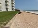 A pristine beach with soft sand next to a grassy lawn area that leads up to a condominium complex at 5201 S Atlantic Ave # 407A, New Smyrna Beach, FL 32169