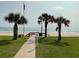 Beach access featuring a grassy area with palm trees and ocean view at 5201 S Atlantic Ave # 407A, New Smyrna Beach, FL 32169