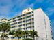 A multi-story condo complex with white walls, yellow trim, and palm trees in front of the building at 5201 S Atlantic Ave # 407A, New Smyrna Beach, FL 32169