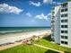 Building exterior with oceanfront view, balconies, and manicured lawn and landscaping at 5201 S Atlantic Ave # 407A, New Smyrna Beach, FL 32169