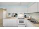 Well-lit kitchen featuring white cabinetry, matching appliances, and convenient access to the living area at 525 N Atlantic Ave # 39, New Smyrna Beach, FL 32169