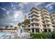 Building exterior featuring balconies, a pool area, and palm trees against a cloudy sky at 5301 S Atlantic Ave # 140, New Smyrna Beach, FL 32169
