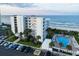 Coastal condo building featuring an outdoor pool, palm trees, and an ocean view at 5301 S Atlantic Ave # 140, New Smyrna Beach, FL 32169
