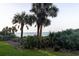 View of the lawn with palm trees and lush vegetation along the ocean at 5301 S Atlantic Ave # 140, New Smyrna Beach, FL 32169